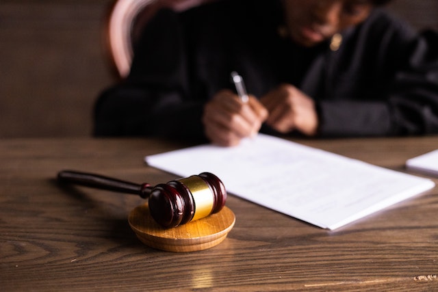 a black judge reviews a document at their desk upon which sits a wooden gavel